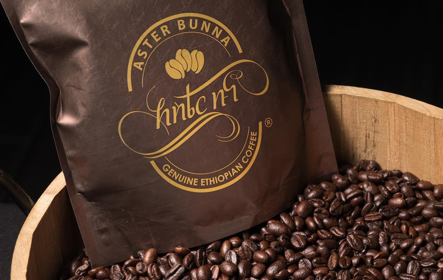 Professional Photographer A brown bag labeled Aster Bunna Genuine Ethiopian Coffee rests in a wooden container filled with dark roasted coffee beans, perfect as a backdrop for headshots or pet photography with a rich, artisanal touch. www.maranonimagery.com