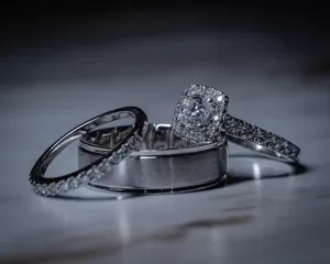 Professional Photographer Three silver rings rest on a marble surface: a plain band, a diamond-studded band, and a diamond engagement ring with a square-shaped halo setting—perfect details for wedding photography. www.maranonimagery.com