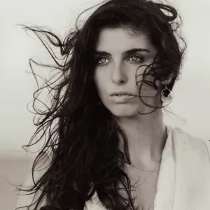 Professional Photographer A woman with long, dark hair blown by the wind gazes into the distance. She wears hoop earrings and a light-colored top. The black and white portrait captures a dramatic, emotional mood, reflecting the photographer’s eye for evocative portaits. www.maranonimagery.com