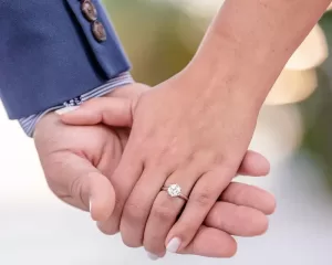 Professional Photographer Close-up of two people holding hands, with one wearing a suit sleeve and the other showing a diamond engagement ring—perfect for capturing intimate moments in wedding photography. www.maranonimagery.com