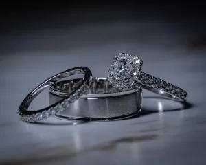 Professional Photographer Three silver rings rest on a marble surface: a plain band, a band with small stones, and a diamond engagement ring with a square halo—perfect accents for wedding photography. www.maranonimagery.com