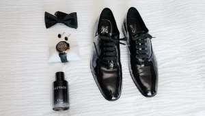 Professional Photographer Men’s formal accessories arranged on a white surface: a black bow tie, cufflinks, a wristwatch, sleek dress shoes, Dior Sauvage cologne—perfect props for any photographer specializing in classy portraits or sophisticated headshots. www.maranonimagery.com