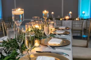 Professional Photographer A formal table setting with gold-rimmed plates, white napkins, and silver cutlery. Water and wine glasses glisten as candles and greenery add elegance—perfect for a photographer to capture stunning headshots in this warm atmosphere. www.maranonimagery.com