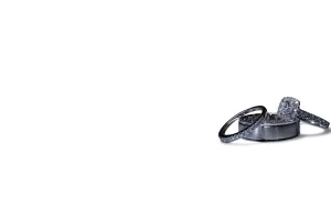 Professional Photographer Three silver rings with embedded stones rest on a small, round, silver stand in the lower right corner of a mostly white background—elegant accessories perfect for portraits or headshots. www.maranonimagery.com