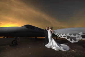Professional Photographer A bride and groom stand in front of a private jet at sunset, their formal wedding attire glowing in the dramatic light. This stunning moment captures the essence of Wedding Photography, with the bride’s veil flowing softly to the side. www.maranonimagery.com