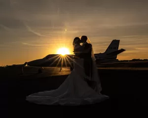 Professional Photographer Silhouetted bride and groom embrace in front of a private jet at sunset, the sun casting a golden glow—an unforgettable moment captured through stunning wedding photography. www.maranonimagery.com
