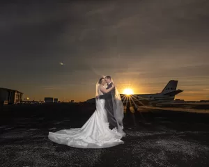 Professional Photographer A bride and groom embrace on an airstrip at sunset, the bride’s veil flowing as a private jet glows in golden light—an unforgettable moment as timeless as the finest portraits. www.maranonimagery.com