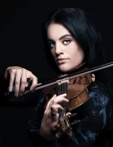 Professional Photographer A person with long dark hair and a nose ring plays a violin, gazing confidently at the camera against a dark background—an artistic portrait perfect for any photographer specializing in captivating portraits or wedding photography. www.maranonimagery.com