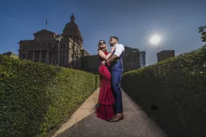 Professional Photographer A couple poses together on a pathway surrounded by green hedges, with a domed government building in the background and the sun shining brightly—an ideal setting for romantic portraits or elegant headshots. www.maranonimagery.com