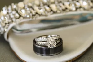 Professional Photographer A close-up of three wedding rings—two diamond-studded bands and a dark metal band—stacked together in front of a sparkling, decorative background, perfect for Wedding Photography portfolios. www.maranonimagery.com