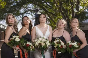 Professional Photographer Five women, including a bride in a white dress, stand outdoors holding flower bouquets and making playful kissy faces at the camera. This fun moment captures the artistry of wedding photography with headshots full of personality. www.maranonimagery.com