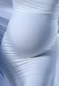Professional Photographer A close-up of a pregnant belly wrapped in smooth, white fabric, highlighting the gentle curves and contours. Perfect for maternity portraits by a professional photographer, the soft drape creates an elegant and serene appearance. www.maranonimagery.com