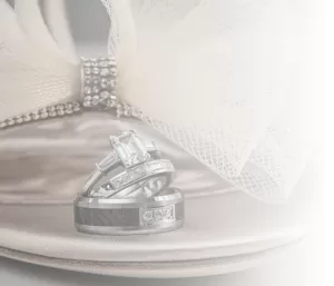 Professional Photographer Three silver rings, including a diamond engagement ring, rest on a satin high-heeled shoe with a jeweled strap and mesh bow, beautifully captured by a professional photographer in soft, light tones. www.maranonimagery.com