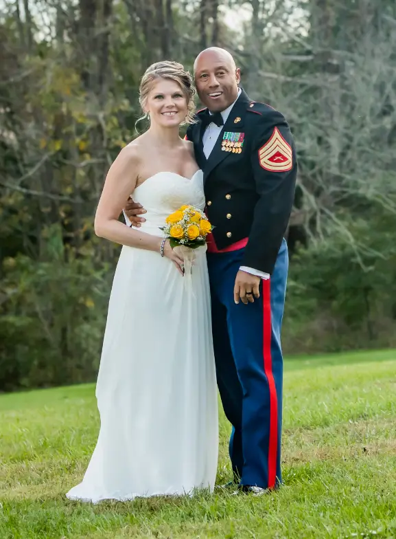 Professional Photographer A bride in a strapless white gown and a groom in a military dress uniform stand arm in arm on grass, smiling at the camera with trees in the background, beautifully captured by their photographer. www.maranonimagery.com