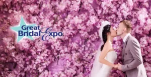 Professional Photographer A bride and groom kiss in front of a vibrant wall filled with pink cherry blossoms, captured beautifully by a skilled photographer. The Great Bridal Expo logo appears on the left side of the image. www.maranonimagery.com